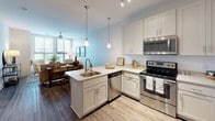 Located on Shucker Circle in Mount Pleasant, South Carolina, this single-floor residence offers a thoughtfully designed layout with a cohesive, contemporary aesthetic throughout. The open-concept kitchen is a standout feature, showcasing white shaker cabinetry, light quartz countertops, a peninsula with seating, and a full suite of stainless steel appliances, including a range, microwave, dishwasher, and refrigerator. Pendant lighting above the peninsula and track lighting overhead add both function and style, while wood-look flooring grounds the space warmly.

The kitchen flows seamlessly into the living area, which benefits from large windows fitted with horizontal blinds, allowing generous natural light to fill the room. The living space provides a comfortable, airy atmosphere well-suited for relaxing or entertaining.

The bedroom is carpeted and generously sized, featuring large windows that invite natural light and views of surrounding greenery. Neutral wall tones and clean lines contribute to a calm, restful environment.

The bathroom is finished with large-format tile flooring, a tiled tub-and-shower combination, a white vanity with quartz-style countertops, and polished chrome fixtures, delivering a clean and functional design. Overall, the residence presents a bright, modern interior with consistent finishes throughout.