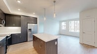 Located at 6000 Luminary Drive in Chula Vista, CA, this well-appointed 2-bedroom, 2-bathroom residence offers a thoughtfully designed single-level layout. The open-concept kitchen and living area serves as the heart of the home, showcasing dark wood cabinetry, a white quartz-topped center island with pendant lighting, a white tile backsplash, and stainless steel appliances including a french-door refrigerator with water dispenser. Light wood-style flooring flows throughout, complementing the clean, neutral color palette. Large windows in the living area and bedrooms invite natural light and provide views of the surrounding neighborhood. The primary bedroom offers a comfortable footprint with a dedicated closet featuring built-in shelving and hanging rods. Both bathrooms are finished with white tile surrounds and tub-shower combinations with brushed nickel fixtures. Three closets total provide ample storage throughout the home. Additional highlights include a private balcony, in-unit laundry, and a hallway that efficiently connects all rooms. The overall ambiance is clean, contemporary, and move-in ready.