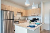 Located at 4542 Thurston Ln in Fitchburg, WI, this well-appointed 2-bedroom, 2-bathroom single-floor residence offers a thoughtfully designed layout that balances comfort and functionality. The open-concept kitchen and living area serves as the heart of the home, highlighted by a granite-topped island with pendant lighting, light maple cabinetry, stainless steel appliances including a refrigerator and dishwasher, and durable light wood-style flooring that flows throughout the main living spaces. A sliding glass door in the living room opens to a private patio overlooking a landscaped courtyard with a community playground, bringing in an abundance of natural light and outdoor connectivity. The two bedrooms are carpeted for comfort, each offering clean white walls and windows that frame views of the surrounding community. The primary bedroom provides a generous footprint with ample room for furnishings. Both bathrooms feature light wood vanities, white countertops, large mirrors, and chrome fixtures, maintaining a clean and consistent aesthetic. A dedicated hallway and closet add to the practical storage options throughout. The overall ambiance is bright, modern, and move-in ready, with a neutral palette that suits a variety of interior styles.