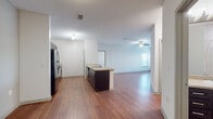 This single-floor residence offers a thoughtfully designed open-concept layout that seamlessly connects the kitchen and living areas. The kitchen is anchored by a central island with a sink and dark cabinetry, complemented by a black refrigerator and ample counter space. Wood-look flooring flows throughout the main living areas, adding warmth and continuity, while the spacious living room benefits from natural light streaming through multiple windows and a ceiling fan overhead.

The bedrooms are carpeted for comfort and each features a ceiling fan with light fixture and generously sized windows with blinds that allow for abundant natural light. At least one bedroom includes a walk-in closet with built-in shelving, providing excellent storage. An additional smaller bedroom offers a walk-in closet as well, making it versatile for use as a guest room or home office.

Two full bathrooms serve the residence, each finished with dark wood cabinetry, light-toned countertops, wood-look flooring, and a tub/shower combo with clean white surrounds. One bathroom features a large vanity mirror and a dual-sink setup, offering added convenience. Overall, the space presents a clean, neutral palette with consistent finishes throughout, creating a bright and functional living environment.