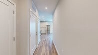 Located at 1900 S Hanover St in Baltimore's South Baltimore neighborhood, this well-appointed one-bedroom, one-bathroom unit offers a clean, modern aesthetic throughout. Warm hardwood-style flooring flows seamlessly across every room, complementing the neutral color palette and crisp white trim.

The open-concept kitchen and living area serves as the heart of the unit. The kitchen is outfitted with white shaker-style cabinetry extending to the ceiling, a classic white subway tile backsplash, and a full suite of stainless steel appliances including a refrigerator, range, microwave, and dishwasher. Recessed lighting illuminates the space effectively.

A hallway connects the main living area to the bedroom, bathroom, and closet. The bedroom is a comfortable size, featuring large windows that invite abundant natural light and views of the surrounding urban streetscape. An adjacent walk-in closet provides well-organized storage with built-in shelving and hanging rods.

The bathroom is sleek and modern, finished with large-format light tile flooring, a glass-enclosed walk-in shower with tile surround, a white vanity with solid surface countertop, and recessed lighting overhead. Every detail of this unit reflects contemporary finishes and functional design.
