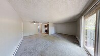 Located at 4455 NE 12th St in Renton, WA, this single-floor residence offers three bedrooms and one bathroom within a thoughtfully arranged floor plan. Throughout the home, soft neutral-toned carpeting and light gray walls create a clean, cohesive aesthetic. Textured ceilings are consistent throughout, adding a classic character to each room.

The spacious primary bedroom is a standout feature of this home, offering generous proportions well-suited for a full furniture arrangement. It includes a sliding glass door that opens to a private patio, inviting natural light and outdoor access. A baseboard heater ensures year-round comfort. The two additional bedrooms are well-sized, each carpeted and featuring windows that bring in natural light. One bedroom includes a closet and direct hallway access, while another benefits from a sliding closet and an in-unit stacked washer and dryer — a highly practical convenience.

The bathroom is clean and functional, featuring a full-size soaking tub and shower combination with chrome fixtures. The kitchen, visible in the dollhouse view, features dark cabinetry and flows into the main living areas. A ceiling fan in the central living area enhances airflow throughout. Baseboard heating is present in multiple rooms, providing consistent warmth. The layout is connected by a central hallway, making navigation between rooms efficient and straightforward.
