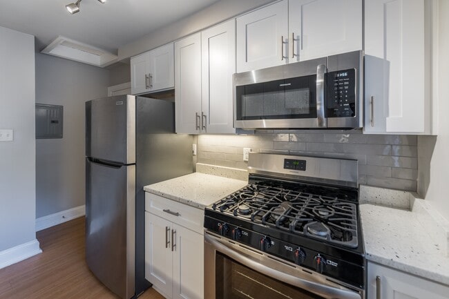 The Cary renovated kitchen with white cabinets, stainless steel appliances and a microwave - Malvern Manor Apartments