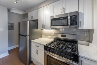 The Cary renovated kitchen with white cabinets, stainless steel appliances and a microwave - Malvern Manor Apartments