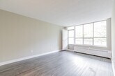 Located at 40 Tuxedo Crt in Toronto's Scarborough neighbourhood, this 2-bedroom, 1-bathroom unit offers a functional and well-appointed single-floor layout. Throughout the space, durable hardwood-style flooring and neutral warm-beige walls create a clean, cohesive aesthetic complemented by textured ceilings and crisp white baseboards.

The spacious living room is a standout feature, boasting a large floor-to-ceiling window wall that floods the area with natural light and frames serene views of mature, lush trees. A hallway connects the living area to the rest of the unit, providing a natural flow between spaces.

The primary bedroom is generously sized and includes a large window overlooking greenery, along with a baseboard heating unit. The second bedroom also benefits from natural light through its own window with similarly peaceful tree views. Both rooms offer a calm, comfortable atmosphere.

The kitchen features white cabinetry with modern bar-pull hardware, a double stainless steel sink, stone-finish countertops, and a subtle tile backsplash — offering both style and practicality. The unit is completed by a full bathroom with a tiled tub-and-shower combination and a small privacy window for ventilation. A dedicated closet and entry hallway round out the layout.
