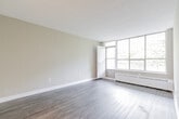 Located at 40 Tuxedo Crt in Toronto's Scarborough neighbourhood, this 2-bedroom, 1-bathroom unit offers a functional and well-appointed single-floor layout. Throughout the space, durable hardwood-style flooring and neutral warm-beige walls create a clean, cohesive aesthetic complemented by textured ceilings and crisp white baseboards.

The spacious living room is a standout feature, boasting a large floor-to-ceiling window wall that floods the area with natural light and frames serene views of mature, lush trees. A hallway connects the living area to the rest of the unit, providing a natural flow between spaces.

The primary bedroom is generously sized and includes a large window overlooking greenery, along with a baseboard heating unit. The second bedroom also benefits from natural light through its own window with similarly peaceful tree views. Both rooms offer a calm, comfortable atmosphere.

The kitchen features white cabinetry with modern bar-pull hardware, a double stainless steel sink, stone-finish countertops, and a subtle tile backsplash — offering both style and practicality. The unit is completed by a full bathroom with a tiled tub-and-shower combination and a small privacy window for ventilation. A dedicated closet and entry hallway round out the layout.