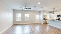 This two-story home offers an impressive six bedrooms and four bathrooms, thoughtfully arranged across two floors to maximize both space and functionality. The main level features an open living area with light-toned luxury vinyl plank flooring, a ceiling fan with light fixture, recessed lighting, and multiple windows that bathe the space in natural light. The modern kitchen is a standout feature, showcasing white shaker cabinetry, quartz countertops, a large center island with an undermount sink and brushed gold faucet, stainless steel appliances including a French door refrigerator, and a stylish tile backsplash accented by pendant lighting overhead. A well-organized pantry closet with floor-to-ceiling built-in shelving adds ample storage. The upper floor expands the living space significantly and hosts additional bedrooms, each with ceiling fans and windows offering natural light. Bedrooms feature a mix of luxury vinyl plank and carpet flooring, with dedicated closet space. The bathrooms are elegantly appointed with large-format tile walk-in showers fitted with glass enclosures, quartz vanity tops, undermount sinks, and brushed gold fixtures. Clean white walls, consistent trim work, and cohesive finishes throughout give this home a fresh, contemporary feel.