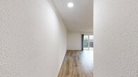 This 400 square foot apartment in Newport Beach offers a thoughtful layout maximizing space and functionality. The living room serves as the focal point, featuring wood-look flooring that adds warmth and durability. Large sliding glass doors flood the space with natural light and provide access to a private balcony, perfect for enjoying the coastal air.

The apartment's design emphasizes clean lines and a neutral color palette, creating a sense of openness. A ceiling fan in the living area aids in air circulation, while a wall-mounted heating unit ensures year-round comfort. The bathroom showcases modern fixtures, including a white vanity with ample storage and a mirror, complementing the overall contemporary aesthetic.

The balcony, while compact, offers an outdoor retreat with a mix of materials including wood paneling and metal railings. This space provides a seamless indoor-outdoor connection, enhancing the apartment's livability.

Despite its modest size, the apartment makes efficient use of every square foot, with clever storage solutions and a well-thought-out floor plan. The result is a cozy yet functional living space ideal for those seeking a low-maintenance lifestyle in the heart of Newport Beach.