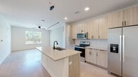 Located at 440 N Monroe St in Tallahassee, FL, this modern 2-bedroom, 2-bathroom single-floor residence offers a thoughtfully designed layout with contemporary finishes throughout. The open-concept kitchen and living area serves as the heart of the home, featuring a large center island with a quartz countertop, undermount sink, and matte black faucet. Light wood cabinetry, a white subway tile backsplash, and a full suite of stainless steel appliances — including a French door refrigerator, electric range, and built-in microwave — complete the sleek kitchen. Light hardwood-style flooring flows through the main living areas, complementing the bright, neutral color palette. The spacious living room offers a clean, open canvas with ample natural light from large windows. Both bedrooms are well-proportioned and carpeted for comfort, each equipped with a ceiling fan and closet. The primary bedroom includes a dedicated closet with built-in shelving, accessible through a stylish barn-style sliding door. The primary bathroom features a glass-enclosed walk-in shower, light wood vanity with quartz countertop, and tile flooring. The second bathroom mirrors the same refined aesthetic. Two closets provide generous storage throughout the unit.