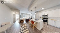This thoughtfully designed 2-bedroom, 3-bathroom single-story residence offers a functional and modern open-concept floor plan. The combined kitchen and living area serves as the heart of the home, where a sleek white kitchen with shaker-style cabinetry, subway tile backsplash, stainless steel appliances, and a quartz-topped island with bar seating flows seamlessly into the living room. The living space is bright and airy, featuring wood-look flooring, a ceiling fan, and large windows with exterior door access that invite natural light throughout. Both bedrooms are comfortably sized, each featuring ceiling fans, large windows, and wood-look flooring. The generously proportioned primary bedroom includes a well-organized walk-in closet with built-in shelving and hanging rods. The bathrooms are finished with clean, contemporary details — one featuring a glass-enclosed walk-in shower with white subway tile and matte black hardware, and another offering a full soaking tub with tiled surround. A dedicated laundry room houses a full-size washer and dryer with overhead cabinetry, adding everyday convenience. A central hallway connects all areas of the home, completing this efficient and stylish layout.