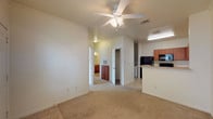 This single-floor unit offers a practical and comfortable layout designed for everyday living. The open-concept living area features soft carpeting underfoot and a ceiling fan overhead, flowing seamlessly into the kitchen through a peninsula counter. The kitchen is well-appointed with warm medium-toned wood cabinetry, generous counter space, and a full suite of black appliances including a refrigerator, range, microwave, and dishwasher. Light tile flooring ties the kitchen together, and ample upper and lower cabinets provide plenty of storage.

The living area is filled with natural light from a large front-facing window, complemented by a ceiling fan and a private entry door. The bedrooms are carpeted and bright, each featuring windows with blinds that invite natural light while maintaining privacy. The primary bedroom is notably spacious, with multiple windows and a ceiling fan, and connects to a generous walk-in closet outfitted with wire shelving for organized storage.

The bathroom is finished with tile flooring, warm wood vanity cabinetry, a wide mirror, and a shower-tub combo. Throughout the unit, clean white walls and consistent finishes create a cohesive and move-in-ready atmosphere.