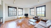 This 860 square foot apartment, located at 80 E Van Buren St in Chicago, offers a blend of compact living and modern amenities. The space features three bedrooms and three bathrooms, efficiently arranged on a single floor. The primary bedroom, measuring 110 square feet, provides a cozy retreat.

The apartment's standout feature is its large windows, offering breathtaking views of the Chicago skyline and Lake Michigan. These windows flood the living areas with natural light, creating an open and airy atmosphere. The living room is furnished with contemporary pieces, including a sleek gray sofa and armchair, complemented by a modern coffee table.

The bedrooms are designed for functionality, with simple wooden beds, desks, and chairs, ideal for students or young professionals. Each room has a window, some with city views, maintaining a bright and inviting ambiance throughout the space.

The bathrooms are clean and modern, featuring white fixtures and tiled surfaces. Some bathrooms include a combination tub-shower, while others have a stand-alone shower, offering variety in the compact space.

Throughout the apartment, hardwood floors add warmth and character, contrasting nicely with the crisp white walls. Track lighting in the living areas provides adjustable illumination options. The overall design prioritizes efficiency and modern urban living, making excellent use of the available square footage in this prime downtown Chicago location.