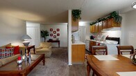 This single-floor, one-bedroom, one-bathroom residence offers a practical and comfortable layout across a thoughtfully organized floor plan. The living room serves as the central gathering space, featuring wall-to-wall carpeting, a textured ceiling, and room for a full seating arrangement centered around a classic wood coffee table. The space flows openly toward a defined dining area, which features wood-look flooring, a pendant light fixture overhead, and a window that brings in natural light.

The galley-style kitchen runs parallel along one side, offering ample honey-toned wood cabinetry extending to the ceiling for generous storage. White appliances include a refrigerator, electric range, and dishwasher, all complemented by light countertops and a dual-basin sink.

The bedroom is a calm retreat with plush carpeting, a window with natural light, and a louvered double-door closet offering substantial storage. The full bathroom includes a wood-vanity with a single sink, a tub-shower combination with white tile surround, and wood-look flooring, completing the unit's functional design.
