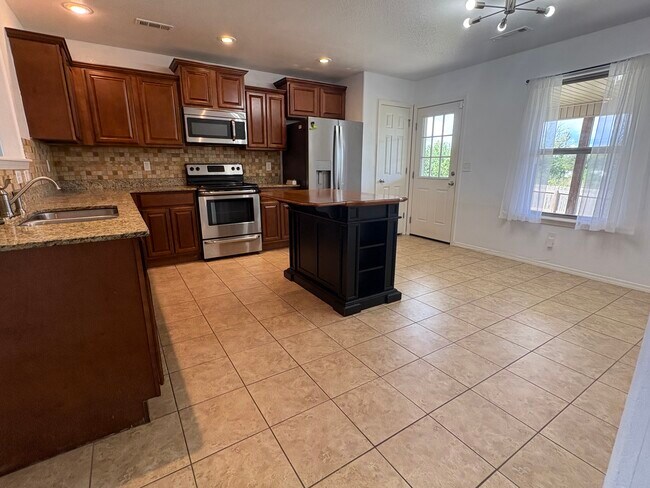 La cocina incluye lavavajillas, estufa eléctrica, refrigerador, rincón para comer, despensa e isla ajustable. - 4208 SW Fieldstone Blvd