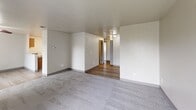 Located at 908 76th St E in Tacoma, WA, this single-floor unit offers three bedrooms, three bathrooms, and a practical layout designed for comfortable everyday living. The living room serves as the heart of the home, featuring plush carpeting, a window with natural light, and a classic fireplace framed in a dark surround — an inviting focal point for relaxing evenings. The kitchen is well-appointed with warm wood-toned cabinetry, a full suite of white appliances including a refrigerator and electric range, a sink with countertop workspace, and an adjacent open shelving area ideal for pantry storage. Wood-style flooring runs through the kitchen and hallway areas, creating a clean transition between spaces. Each of the three carpeted bedrooms offers windows with outdoor views and generous closet space, including sliding double-door closets. The primary bedroom is comfortably sized with ample room for furnishings. The bathrooms are clean and functional, featuring tub-shower combinations with chrome fixtures. A dedicated laundry area accommodates a full-size washer and dryer, adding everyday convenience. The overall aesthetic is neutral and move-in ready, with light walls and consistent finishes throughout.