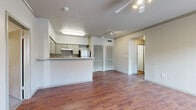 This single-story unit in Leander, Texas, offers a practical and well-organized layout across three bedrooms and two bathrooms. The open-concept living and kitchen area forms the heart of the home, where rich wood-look flooring extends throughout, complemented by neutral white walls and track lighting overhead. The kitchen features gray cabinetry, a peninsula with counter seating, and stainless steel appliances including a refrigerator and range, with louvered closet doors nearby providing additional storage.

The living area flows seamlessly from the kitchen, offering a clean, versatile space with a front entry door and access to adjacent rooms via a connecting hallway. The bedrooms are carpeted and offer a comfortable, quiet retreat; secondary bedrooms include windows for natural light and individual closets, while the primary bedroom benefits from a spacious walk-in closet with wire shelving systems. Both bathrooms feature wood-look tile flooring, gray vanity cabinetry, and tub-shower combinations with white tile surrounds. A dedicated laundry room includes washer and dryer connections, completing the functional layout of this well-appointed Leander residence.