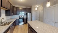 This single-floor residence at 8912 Inverness Bay Road in Charlotte, NC offers a thoughtfully designed layout with contemporary finishes throughout. The kitchen serves as a central highlight, showcasing dark espresso shaker-style cabinetry extending to the ceiling for ample storage, light granite countertops, and a full suite of stainless steel appliances including a refrigerator, range, microwave, and dishwasher. A center island with matching granite provides additional prep space and is accented by pendant lighting overhead. Light-toned hardwood-style flooring flows through the kitchen and common areas, creating a warm, cohesive aesthetic.

The bedrooms are finished with plush neutral carpet and ceiling fans, and each receives natural light through sizable windows with exterior views of surrounding greenery. The primary bedroom connects to an en-suite bathroom featuring a vanity with granite countertops, dark cabinetry, a soaking tub, and separate shower, all set on light wood-style flooring. A secondary bathroom mirrors the quality with a tiled walk-in shower. Multiple walk-in closets with wire shelving systems offer generous, organized storage throughout the home.
