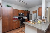 Located in Cottonwood Heights, Utah, this single-floor residence offers a thoughtfully designed layout with a warm, cohesive aesthetic throughout. The open-concept living and dining area is anchored by rich hardwood flooring, large windows dressed with layered curtains, and a ceiling fan that enhances the comfortable atmosphere. Natural light fills the space generously, highlighting the neutral color palette on the walls.

The dining area sits adjacent to the kitchen, connected by a breakfast bar overhang. The kitchen features warm-toned wood cabinetry, stainless steel appliances including a built-in microwave and electric range, and hardwood flooring that carries through from the main living areas.

A versatile den or office provides a carpeted retreat with ample natural light, offering flexibility for various uses. The bedroom area includes access to a walk-in closet with built-in shelving, providing substantial storage. The bathroom features a full tub-shower combination with tile surround detailing and hardwood flooring.

An in-unit laundry closet with side-by-side washer and dryer, along with overhead shelving, adds everyday convenience to this well-appointed Cottonwood Heights residence.