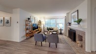 This thoughtfully designed single-floor residence offers a cohesive blend of comfort and modern style throughout its well-organized layout. The living room serves as the heart of the home, featuring light hardwood flooring, a fireplace, and large windows fitted with horizontal blinds that invite an abundance of natural light. The space is anchored by a warm wood media console and coordinating ladder shelves, complemented by a comfortable neutral sofa and a pair of contemporary accent chairs.

The kitchen is outfitted with crisp white shaker cabinetry, grey quartz countertops, and stainless steel appliances, including a range and refrigerator. It flows seamlessly into the dining area, which is brightened by a pendant light overhead and features sliding glass doors opening to an outdoor patio. The primary bedroom is a serene retreat, benefiting from dual windows with garden views and ample floor space. A dedicated vanity nook provides a private grooming area with framed artwork and a decorative mirror. The bathroom includes a glass-enclosed walk-in shower and tile flooring. A secondary bedroom features a loft bed configuration, maximizing space with colorful wall-mounted storage and a cozy lounge area below, making it highly functional and versatile.