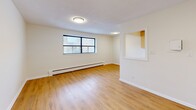 Located at 2417 Hurontario St in Mississauga, this well-laid-out one-bedroom, one-bathroom unit offers a functional and comfortable living experience across a single floor. The open living room is bright and welcoming, finished with warm light hardwood flooring and neutral cream-toned walls that run throughout the unit. Large windows invite natural light and provide views of the surrounding neighbourhood, complemented by baseboard heating units along the walls. The galley-style kitchen is efficiently designed with light wood cabinetry, ample upper and lower storage, white countertops, a double sink, and white appliances including a stove and refrigerator. A pass-through window connects the kitchen to the living area, enhancing the sense of openness. The bedroom is a comfortable, quiet retreat featuring its own window, a radiator, hardwood flooring, and a closet with sliding doors. The bathroom is clean and practical, appointed with full-wall ceramic tile surrounding a soaker tub and shower combination, along with a white vanity. A hallway connects all areas of the unit smoothly. The space is finished consistently throughout with light tones and hardwood flooring, creating a cohesive and easy-to-maintain environment.