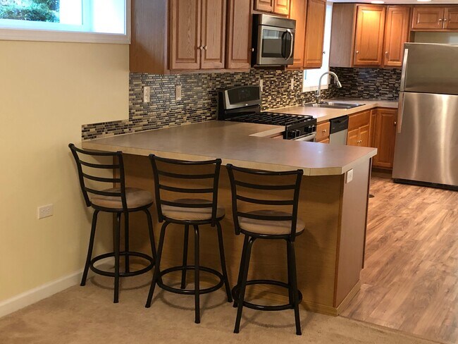 Gran cocina abierta con estufa de gas, lavavajillas y barra para comer. - 5409 Beacon Avenue South