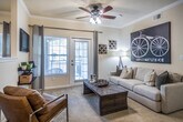 This single-floor, 2-bedroom, 2-bathroom residence in Memphis, Tennessee offers a thoughtfully designed layout with a warm, neutral color palette and carpeted living areas throughout. The living room serves as the heart of the home, featuring crown molding, a ceiling fan with light fixture, and a glass-paned door that opens to a private outdoor patio, allowing natural light to fill the space. Built-in wall shelving adds both character and functional storage.

The kitchen is equipped with ample honey-toned wood cabinetry, granite-style countertops, tile flooring, and white appliances including a dishwasher, range, and microwave. An adjacent dining area with crown molding and a large window provides a comfortable space for meals. The open-concept flow connecting the kitchen, dining, and living areas is enhanced by track lighting and additional built-in shelving.

Both bedrooms are generously sized with plush carpet, ceiling fans, and large windows that invite natural light. The two bathrooms feature tile flooring, wood vanity cabinetry, and granite-style countertops. A dedicated in-unit laundry room with built-in shelving and full-size washer and dryer hookups adds everyday convenience to this practical and comfortable home.