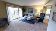 This renovated two-bedroom, one-bathroom residence offers a well-designed single-floor layout that balances comfort and functionality. The living room is a welcoming space finished with neutral-toned carpet and warmed by abundant natural light streaming through large sliding glass doors that open onto a private balcony, providing pleasant outdoor views of the surrounding neighborhood. The open sightlines create an airy, comfortable atmosphere ideal for relaxing or entertaining.

The kitchen has been thoughtfully updated with rich, dark-stained cabinetry, granite-style countertops, and stainless steel appliances, including a gas range and dishwasher. Hardwood-style flooring, recessed lighting, and a double-basin sink complete the polished, functional space.

Adjacent to the kitchen, the dining area accommodates a full-sized table and benefits from a central overhead light fixture, creating a defined yet open space that flows naturally between the kitchen and living areas. Artwork-adorned walls throughout add a curated, intentional aesthetic to the home.

The two bedrooms offer comfortable retreats with carpeted flooring consistent with the living areas. Overall, the residence presents a clean, modern finish throughout, making it a move-in ready space with thoughtful updates and a cohesive design.