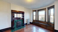Located at 66 Adelaide St in Detroit's Midtown area, this two-bedroom, one-bathroom residence beautifully preserves its historic character throughout. Rich hardwood floors extend across the single level, complemented by dark-stained wood trim, paneled interior doors with brass hardware, and elegant crown molding that frame each room with classic craftsmanship.

The living room serves as the centerpiece of the home, showcasing a striking decorative fireplace with a dark wood mantle and distinctive emerald green tile surround. A built-in window bench and a bay window configuration flood the space with natural light and offer charming neighborhood views, while a cast-iron radiator adds to the period aesthetic.

The kitchen features white cabinetry, granite-style countertops, a stainless steel sink and appliances, and a tile backsplash — a clean, functional update within the home's classic framework. A separate dining area provides dedicated space for meals.

The bedrooms are bright and well-proportioned, each with hardwood floors and natural light from windows overlooking the surrounding neighborhood. The primary bedroom features dark wood wainscoting and a radiator consistent with the home's historic detailing.

The bathroom retains its vintage character with a clawfoot tub, mosaic tile flooring, a pedestal sink, and a decorative oval mirror. Two closets and a welcoming entrance complete this well-appointed Detroit residence.