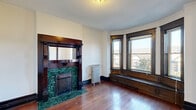 Located at 66 Adelaide St in Detroit's Midtown area, this two-bedroom, one-bathroom residence beautifully preserves its historic character throughout. Rich hardwood floors extend across the single level, complemented by dark-stained wood trim, paneled interior doors with brass hardware, and elegant crown molding that frame each room with classic craftsmanship.

The living room serves as the centerpiece of the home, showcasing a striking decorative fireplace with a dark wood mantle and distinctive emerald green tile surround. A built-in window bench and a bay window configuration flood the space with natural light and offer charming neighborhood views, while a cast-iron radiator adds to the period aesthetic.

The kitchen features white cabinetry, granite-style countertops, a stainless steel sink and appliances, and a tile backsplash — a clean, functional update within the home's classic framework. A separate dining area provides dedicated space for meals.

The bedrooms are bright and well-proportioned, each with hardwood floors and natural light from windows overlooking the surrounding neighborhood. The primary bedroom features dark wood wainscoting and a radiator consistent with the home's historic detailing.

The bathroom retains its vintage character with a clawfoot tub, mosaic tile flooring, a pedestal sink, and a decorative oval mirror. Two closets and a welcoming entrance complete this well-appointed Detroit residence.