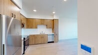 Located at 900 Chestnut St in Redwood City, CA, this thoughtfully designed one-bedroom, one-bathroom unit offers a efficient and modern living experience across a single floor. Light wood flooring flows seamlessly throughout every room, creating a warm, cohesive aesthetic.

The kitchen is a standout feature, showcasing flat-front warm wood cabinetry that extends to the ceiling for generous storage. A full suite of stainless steel appliances — including a refrigerator, range with oven, microwave, and dishwasher — is complemented by white countertops and a clean tile backsplash. Recessed lighting illuminates the space efficiently.

The bedroom is bright and airy, benefiting from a large window that invites natural light and frames views of the surrounding Redwood City skyline and greenery. A wall-mounted mini-split HVAC unit provides individual climate control. A sliding closet door adds a sleek, space-conscious touch.

The bathroom continues the warm wood cabinetry theme with a vanity featuring a white countertop and an oversized mirror. Clean white walls and the same light wood flooring maintain a unified, contemporary feel throughout.

The overall ambiance of the unit is clean, minimal, and modern — ideal for those seeking a well-appointed residence in the heart of Redwood City.