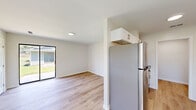 Located at 215 Martin St in Georgetown, SC, this single-story, one-bedroom, one-bathroom home offers a clean and modern interior with a thoughtfully designed layout. Light wood-tone flooring runs throughout the home, creating a cohesive and bright atmosphere across all rooms.

The living area is open and airy, highlighted by a sliding glass door that floods the space with natural light and provides direct access to the outdoors, offering views of the surrounding greenery. Two interior doors near the entry provide access to the utility room and a closet, keeping the layout organized and functional.

The galley-style kitchen is well-appointed with white shaker cabinetry, granite countertops, a stainless steel refrigerator, dishwasher, and a single-basin sink — providing ample storage and a clean, contemporary aesthetic.

The bedroom is a comfortable size, featuring a ceiling fan with a light fixture, a large window with outdoor views of mature trees, and access to a dedicated closet. The room maintains the same light flooring and neutral wall tones found throughout the home.

The bathroom includes a tub-shower combination with white tile surround and brushed nickel fixtures, a white vanity, and a toilet — all finished in a crisp, clean style. A utility room completes the floor plan, adding practical storage and functionality to this efficient home.