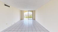 Located in Miami, FL, this 2-bedroom, 1-bathroom apartment offers a well-organized single-floor layout with a clean, neutral aesthetic throughout. The living room is bright and open, featuring white tile flooring and a sliding glass door that opens to a private balcony with views of the surrounding community and lush greenery — a standout feature that brings natural light and a sense of openness to the space. A built-in wall niche adds a subtle architectural detail to the living area.

The kitchen is equipped with white cabinetry, a smooth-top electric range, refrigerator, and a sink, all set beneath a classic drop ceiling with ample upper and lower cabinet storage. Both bedrooms feature light wood-style flooring and textured ceilings, with large windows that invite natural light and offer pleasant exterior views of the tropical surroundings. The primary bedroom is generously sized and includes a dedicated closet with a full-width hanging rod for storage.

The bathroom is fitted with tile flooring, a tub-shower combination with decorative tile surround featuring accent mosaic detailing, and a vanity with cabinet storage. Hallways connect the rooms efficiently, completing a practical and comfortable floor plan ideal for Miami living.