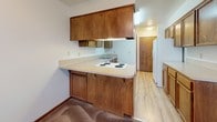 This two-floor home offers a practical and comfortable layout with consistent finishes throughout. The main living area is a standout space, featuring soaring vaulted ceilings, plush carpeting, and a tile-surround fireplace that serves as a natural focal point. A sliding glass door floods the room with natural light and provides direct views of the surrounding greenery. The kitchen is efficiently designed with warm wood cabinetry extending to the ceiling, a built-in coil cooktop, ample counter space, light hardwood-style flooring, and a white refrigerator. It opens conveniently toward the living and dining areas. The carpeted bedrooms are well-sized, each featuring dark-trimmed windows that frame views of mature trees and the surrounding neighborhood, providing a calm and natural atmosphere. Wood-trimmed doors and dark baseboards run consistently throughout the home, lending a cohesive, classic aesthetic. The bathroom features an extended vanity with warm wood cabinetry, a large mirror, and light hardwood-style flooring. Upstairs, an open loft-style area overlooks the surrounding space, with large windows offering treetop views. The textured ceilings are present throughout, adding to the home's traditional character.