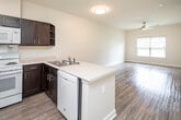 Located on N Country Club Drive in Montgomery, Alabama, this single-story unit offers a well-organized, open-concept layout that connects the kitchen and living areas seamlessly. Wood-style laminate flooring runs throughout the main living spaces and bedrooms, lending a cohesive and clean aesthetic across the unit.

The kitchen is equipped with dark espresso-toned cabinetry offering generous storage, light-colored countertops, a double-basin sink, and white appliances including a range, over-the-range microwave, dishwasher, and refrigerator. A peninsula counter separates the kitchen from the living area, creating a natural flow between the two spaces.

The living area is bright and open, with a ceiling fan and a window fitted with horizontal blinds that allows natural light to filter through. The bedrooms continue the wood-style flooring and each feature ceiling fans and windows with blinds, providing a comfortable and airy feel.

The bathroom features a dark vanity with light countertops, a large mirror, and light tile flooring, maintaining the consistent contrast of dark and light finishes seen throughout the unit. The overall design is clean, functional, and cohesive.