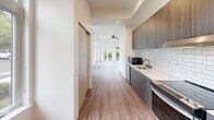 Located at 629 Woodland Square Loop SE in Lacey, WA, this one-bedroom, one-bathroom unit offers a thoughtfully designed single-level layout with modern finishes throughout. Warm-toned luxury vinyl plank flooring runs continuously across the living spaces, lending a cohesive and contemporary feel.

The galley-style kitchen is well-appointed with dark wood grain cabinetry, white subway tile backsplash, light quartz countertops, and stainless steel appliances including a dishwasher, range, and built-in microwave. A single-basin sink anchors the workspace, and ample upper and lower cabinet storage adds practicality.

The open living area extends toward large windows and a glass-panel balcony door, allowing generous natural light and views of surrounding greenery. A ceiling fan provides year-round comfort in this bright, airy space.

The bedroom is a calm, well-lit room with a window overlooking lush landscaping, a ceiling fan, and multiple sliding-panel closets offering substantial storage. Light, neutral walls enhance the sense of openness.

The bathroom is efficiently designed with a soaking tub, and notably includes an integrated laundry area with a full-size washer and dryer. Dark cabinetry with matte black hardware mirrors the kitchen's design language, providing additional storage alongside the vanity with quartz countertops.