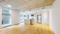 Located at 1020 Rue de Bleury in downtown Montréal, this well-appointed 2-bedroom, 2-bathroom unit offers a modern industrial aesthetic defined by striking exposed concrete ceilings and warm light hardwood flooring throughout. The open-concept living and kitchen area serves as the heart of the unit, bathed in natural light from large floor-to-ceiling windows that frame urban city views. A standout concrete structural column adds architectural character to the living space. The kitchen features white cabinetry, a central island with a built-in sink, stainless steel appliances including a full-size refrigerator and microwave, and a classic white tile backsplash. Both bedrooms continue the clean, minimalist design language with exposed concrete ceilings, hardwood floors, and windows offering city views. The primary bedroom provides a comfortable and private retreat. Two well-finished bathrooms feature large-format neutral stone-look tiles, glass-enclosed walk-in showers with chrome fixtures, and clean white vanities. Two hallways connect the spaces efficiently, each supported by dedicated closets for ample storage. The unit's bright, neutral palette and industrial-modern finishes create a cohesive and contemporary urban living environment.