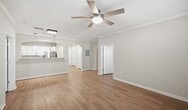 This 980-square-foot, single-floor residence at 141 Park at N Hills St in Raleigh, NC offers 2 bedrooms, 3 bathrooms, and 2 closets in a well-designed layout. The kitchen is appointed with white shaker cabinets, granite countertops, a subway tile backsplash, and a full suite of stainless steel appliances including a range, microwave, dishwasher, and refrigerator. Pendant lighting and an arched pass-through add architectural interest and connect the kitchen to the living area. Warm hardwood-style flooring runs throughout the unit, complemented by neutral gray walls, crown molding, and ceiling fans in the main living spaces and bedrooms. The primary bedroom spans 170 square feet and is served by an en suite bathroom featuring a glass-enclosed walk-in shower and access to a dedicated walk-in closet with built-in shelving. An additional bathroom includes a soaking tub with classic white subway tile surround. Both secondary bedrooms offer natural light through slatted blinds, ceiling fans, and ample space. The unit's open, airy ambiance is enhanced by consistent finishes and a clean, contemporary aesthetic throughout.