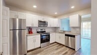Located at 1200 Charleston Green in Malvern, PA, this two-story home offers a thoughtfully arranged layout across two floors. The main level features an inviting entrance that opens to a spacious living room highlighted by durable wood-look flooring and a corner fireplace, creating a warm and functional gathering space. The adjacent kitchen is well-appointed with white shaker cabinetry, subway tile backsplash, stone-look countertops, and a full suite of stainless steel appliances including a refrigerator, range, microwave, and dishwasher. A convenient stacked Whirlpool washer and dryer unit is tucked neatly off the kitchen, and a bathroom completes the main level.

Upstairs, the upper floor houses two generously sized bedrooms, each featuring plush carpeting, natural light from windows with blinds, and ceiling fans for year-round comfort. The spacious primary bedroom offers ample room for a full furniture arrangement. The upper level is served by two additional bathrooms, one of which features marble-style tile flooring, a white vanity, and a tiled tub-shower combination. A hallway connects all upper-level rooms efficiently. The home combines practical amenities with clean, modern finishes throughout.