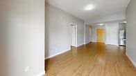 Located at 208 Woolwich St S in Woolwich, Ontario, this well-appointed 2-bedroom, 2-bathroom unit offers a thoughtfully designed open-concept layout finished with contemporary details throughout. Light-toned hardwood flooring flows seamlessly across the entire space, complementing the neutral grey palette on the walls and creating a bright, cohesive atmosphere.

The kitchen is a standout feature, showcasing crisp white shaker-style cabinetry, rich dark granite countertops with a tile backsplash, and a full suite of stainless steel appliances including a refrigerator, range, microwave, and dishwasher. A breakfast bar provides additional counter space and connects the kitchen to the combined dining and living area, which is bathed in natural light from a large sliding glass door leading to the private balcony. The balcony offers serene views of mature evergreen trees and the surrounding landscape.

Both bedrooms are comfortably sized, each featuring windows overlooking the lush treetops, hardwood floors, and ample closet storage — with five closets distributed throughout the unit. The two bathrooms are finished to match the kitchen's aesthetic, with white cabinetry, dark granite vanity tops, and clean tile work. One bathroom features an elegant glass-enclosed corner shower. A dedicated entrance and hallway complete this well-organized, move-in ready home.