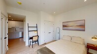 Located at 416 Vine St in Philadelphia's historic Old City neighborhood, this one-bedroom, one-bathroom residence offers a thoughtfully designed layout that maximizes every square foot. The interior is finished in a clean, contemporary palette of crisp white walls and light wood flooring, creating a bright and airy atmosphere throughout.

The bedroom is a comfortable, well-proportioned space featuring a large window that admits generous natural light and offers views of the surrounding cityscape. Recessed lighting and neutral carpeting contribute to the room's calm, restful ambiance. A dedicated closet provides practical storage.

The kitchen is efficiently arranged with white shaker-style cabinetry extending to the ceiling, quartz countertops, a subway tile backsplash, and a full suite of stainless steel GE appliances including a refrigerator, range, and over-the-range microwave. A undermount sink with a brushed gold faucet completes the space.

The bathroom is a standout feature, showcasing a frameless glass walk-in shower with vertically stacked tile surround, mosaic stone flooring, and matte black hardware. A floating wood-toned vanity with a white quartz top and an illuminated mirror add a refined, modern touch. Light tile flooring ties the space together cohesively.