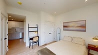 Located at 416 Vine St in Philadelphia's historic Old City neighborhood, this one-bedroom, one-bathroom residence offers a thoughtfully designed layout that maximizes every square foot. The interior is finished in a clean, contemporary palette of crisp white walls and light wood flooring, creating a bright and airy atmosphere throughout.

The bedroom is a comfortable, well-proportioned space featuring a large window that admits generous natural light and offers views of the surrounding cityscape. Recessed lighting and neutral carpeting contribute to the room's calm, restful ambiance. A dedicated closet provides practical storage.

The kitchen is efficiently arranged with white shaker-style cabinetry extending to the ceiling, quartz countertops, a subway tile backsplash, and a full suite of stainless steel GE appliances including a refrigerator, range, and over-the-range microwave. A undermount sink with a brushed gold faucet completes the space.

The bathroom is a standout feature, showcasing a frameless glass walk-in shower with vertically stacked tile surround, mosaic stone flooring, and matte black hardware. A floating wood-toned vanity with a white quartz top and an illuminated mirror add a refined, modern touch. Light tile flooring ties the space together cohesively.