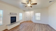 This well-appointed two-story home in Fresno, CA offers three bedrooms, three bathrooms, and a thoughtfully designed layout spread across two floors. The main level features an open-concept living, dining, and kitchen area anchored by warm hardwood-style flooring and crown molding. The living room is highlighted by a classic fireplace with a granite-topped hearth, flanked by large windows with vertical blinds that invite abundant natural light. A ceiling fan adds comfort to the airy space. The kitchen is equipped with rich wood cabinetry, granite countertops, stainless steel appliances including a refrigerator, range, and microwave, and a peninsula with seating — ideal for both everyday living and entertaining. A pantry and laundry room add practical convenience, along with an attached garage with automatic opener. Upstairs, three carpeted bedrooms each feature ceiling fans and generous closet space. The spacious primary bedroom includes an en-suite bathroom and its own closet. The bathrooms are finished with granite vanity tops and warm wood cabinetry, with one bathroom featuring a tub-shower combination with frosted glass doors. Two balconies provide outdoor access, and multiple staircases connect the floors seamlessly throughout this comfortable Fresno residence.