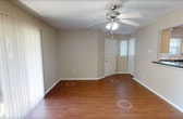 Located at 339 Thomas Dr, Unit B in Newport News, VA, this single-floor apartment offers 720 square feet of functional living space across two bedrooms and one bathroom. The open living room greets you with warm hardwood-style flooring, a ceiling fan with light fixture, and a sliding glass door that allows natural light to fill the space. Adjacent to the living area, the kitchen features light wood cabinetry, dark countertops, a black appliance suite including a refrigerator and range, and track lighting overhead. A peninsula counter connects the kitchen to the living area, creating an open and practical layout. Both bedrooms are finished with plush carpeting and neutral beige walls. The primary bedroom measures 140 square feet and includes a window with blinds for natural light and privacy. The second bedroom also features a window with exterior views. A dedicated closet provides additional storage. The full bathroom is equipped with a soaking tub and shower combo featuring a clean white surround. Textured ceilings are consistent throughout the unit, and white trim accents each room. This apartment offers a straightforward, well-maintained layout suited for comfortable everyday living.