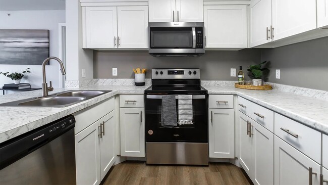 Delight in a culinary escape in our full-equipped kitchens, boasting a sophisticated stainless-steel appliance package including the coveted dishwasher and a mounted microwave over the stove. - Market 1900 Apartment Homes