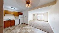 Located at 104 14th St NE in Buffalo, Minnesota, this single-floor, 3-bedroom, 1-bathroom unit offers a practical and efficiently designed layout. The kitchen is well-equipped with warm oak cabinetry providing ample storage, white appliances including a range, dishwasher, and refrigerator, light countertops, a double sink, and durable tile flooring. The kitchen flows openly into the living room, which features plush carpeting, a ceiling fan light fixture, a wall-mounted air conditioning unit, and a large sliding glass door with vertical blinds that invites generous natural light and outdoor access. A baseboard heating system runs throughout the unit. The three bedrooms are carpeted and offer a calm, neutral palette, with the primary bedroom featuring a closet with built-in hanging rods. Additional bedrooms are well-proportioned with easy access to the shared hallway. The bathroom includes a wide vanity with an extended countertop, a large mirror, oak cabinetry below, and tile flooring, complemented by an overhead light fixture. A hallway connects the rooms, offering a closet with folding doors for additional storage. Textured ceilings are present throughout, adding a classic residential character to the space.