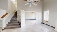 This two-story residence offers a thoughtfully designed layout spread across two floors, combining open living areas with practical amenities. The main floor features a bright and airy living room distinguished by dramatic vaulted ceilings, a ceiling fan, and light hardwood-style flooring. A tile-surround fireplace serves as a central focal point, flanked by windows that invite natural light throughout the space. Double six-panel doors open to connect areas seamlessly, enhancing the open feel of the floor plan. The kitchen is well-appointed with warm wood cabinetry, granite countertops, and a full suite of stainless steel appliances including a range, microwave, dishwasher, and refrigerator. Upstairs, the generously sized primary bedroom features vaulted ceilings, carpeted flooring, a walk-in closet, and a sliding glass door leading to a private balcony with open outdoor views. The upper level also includes a dedicated closet area and convenient access to multiple bathrooms, one of which features tile flooring, a full tub-shower combination, and granite-topped vanity with warm wood cabinetry. With four bathrooms total, this residence provides exceptional functionality for its size, making it a well-rounded and comfortable living space.