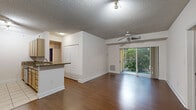 Located in South Miami, this generously proportioned 6-bedroom, 4-bathroom residence is spread across a single floor, offering a well-organized and functional layout. Rich hardwood flooring runs throughout the main living areas and bedrooms, lending warmth and continuity to the interior. The open-concept living room is anchored by a ceiling fan and textured ceiling, and connects seamlessly to a private balcony through sliding glass doors, providing lush, tree-lined outdoor views that bring the Florida greenery indoors. The kitchen features a granite breakfast bar that opens to the living area, light wood cabinetry, and a sink with ample counter space. The spacious primary bedroom includes an en-suite bathroom with a wood-vanity, a large mirror, and convenient access to a dedicated walk-in closet outfitted with wire shelving on multiple levels. Additional bedrooms are bright and airy, each with natural light from plantation-shuttered windows and ceiling fans. The four bathrooms are finished with light tile flooring, wood-tone vanities with marble-style countertops, and tub-shower combinations with white tile surrounds. Two hallways connect the rooms efficiently, and a dedicated closet provides extra storage. The overall ambiance is clean, neutral, and move-in ready.