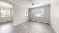 Located at 15400 W Goodyear Blvd in Goodyear, Arizona, this well-appointed one-bedroom, one-bathroom unit offers a thoughtfully designed single-floor layout with a clean, contemporary aesthetic. Wood-look plank flooring runs throughout, complemented by neutral gray walls, crown molding, and crisp white trim.

The open-concept kitchen and living area serves as the heart of the unit. The kitchen features dark, wood-grain cabinetry, bright white quartz countertops, stainless steel appliances including a range, microwave, and dishwasher, and a peninsula with an undermount sink — ideal for both cooking and casual dining. The adjacent living room is bright and open, benefiting from natural light through windows fitted with blinds and a ceiling fan overhead.

The bedroom offers a comfortable, well-proportioned space with wood-look flooring, a ceiling vent, and ample natural light. A dedicated walk-in closet provides generous wire-rack shelving for organized storage. The full bathroom includes a tub/shower combo with a curved curtain rod, a dark-cabinet vanity with a white countertop, and wood-look tile flooring.

A separate laundry room accommodates a full-size side-by-side washer and dryer, adding everyday convenience. A hallway connects the rooms, completing this efficient and modern layout.