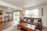 This two-story home offers a thoughtfully designed layout spread across two levels, connected by a central staircase visible in the floor plan. The kitchen is a functional centerpiece, featuring warm oak cabinetry, granite-look countertops, hardwood-style flooring, and stainless steel appliances including a refrigerator, gas range, and dishwasher. A ceiling fan overhead and a casual bar-height dining area complete the space. The living room provides a comfortable gathering area with plush carpet, neutral walls, and natural light from a front-facing window. Two bedrooms are present, each carpeted and well-sized. The primary bedroom benefits from multiple windows that invite generous natural light, a ceiling fan, and ample floor space. The second bedroom is cozy and practical. Two bathrooms serve the home — one full bath with a tub-shower combination, wood-tone vanity, and hardwood-style flooring; and a second bathroom with a similar aesthetic, accented with ocean-themed décor. A dedicated laundry room houses a full-size top-load washer and dryer, adding everyday convenience. Throughout the home, consistent warm-toned finishes, neutral walls, and wood-style flooring in key areas create a cohesive and inviting atmosphere.
