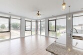 Located at 650 E Elm St in Des Moines, Iowa, this well-appointed one-bedroom, one-bathroom residence offers a thoughtfully designed single-floor layout with a bright, contemporary aesthetic. The open-concept kitchen and living area serves as the heart of the home, highlighted by expansive floor-to-ceiling windows that flood the space with natural light and provide sweeping outdoor views. The kitchen features rich wood cabinetry, stainless steel appliances, a white subway tile backsplash, and a generous granite-topped island with pendant lighting — ideal for both meal preparation and casual dining. Light wood-style flooring flows throughout the main living areas and hallway, complementing the clean, neutral color palette. The spacious primary bedroom is finished with plush carpeting, its own ceiling fan, and large windows that continue the theme of abundant natural light. A dedicated walk-in closet with wire shelving provides ample storage. The bathroom includes wood-style flooring and a dark vanity. A separate laundry room houses a full-sized washer and dryer with overhead shelving for added convenience. The well-lit hallway connects all areas seamlessly, completing this clean and functional modern residence.